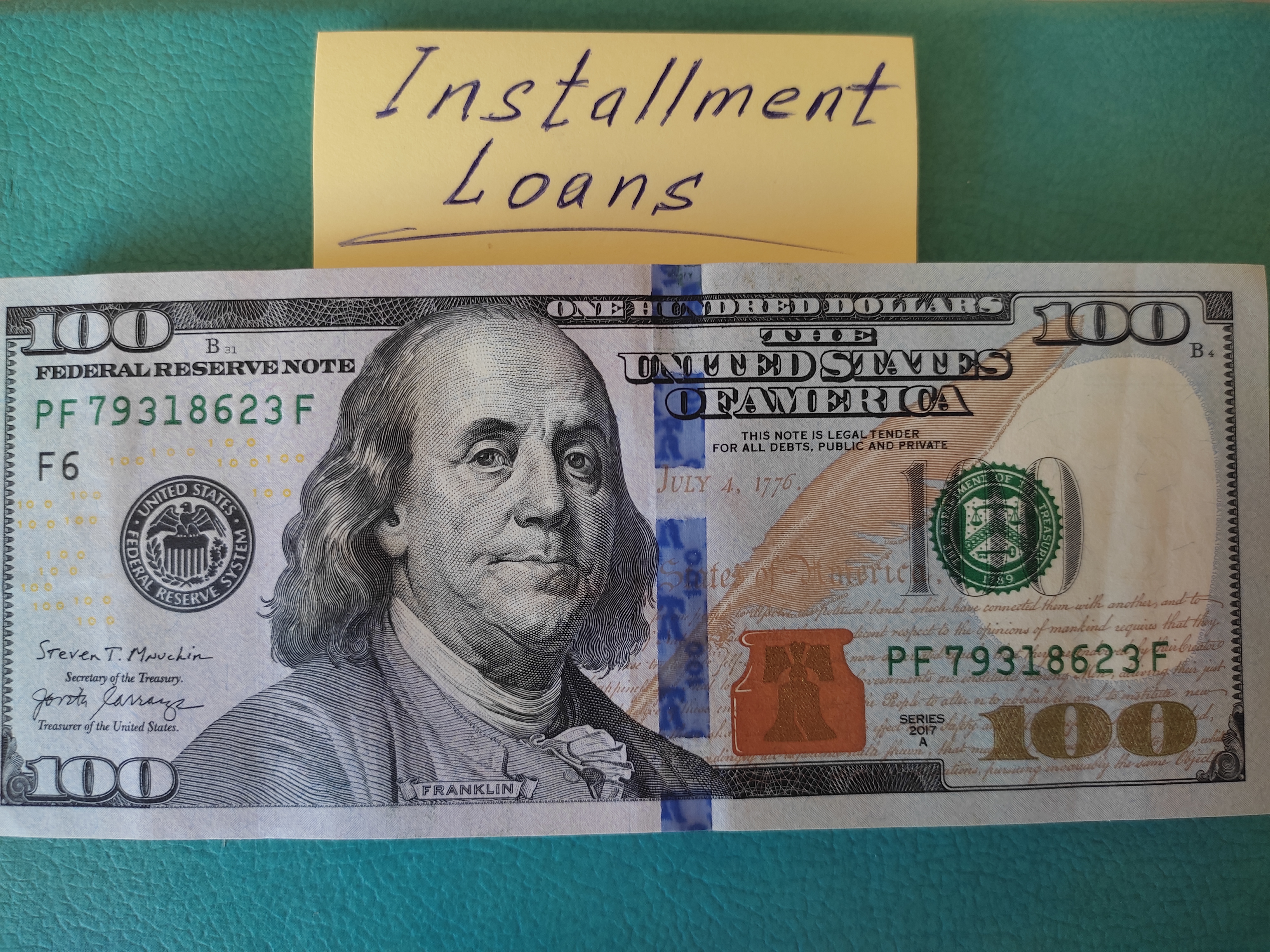 There are dollars on the table, with a yellow sticker and it is written on it - installment loans.
