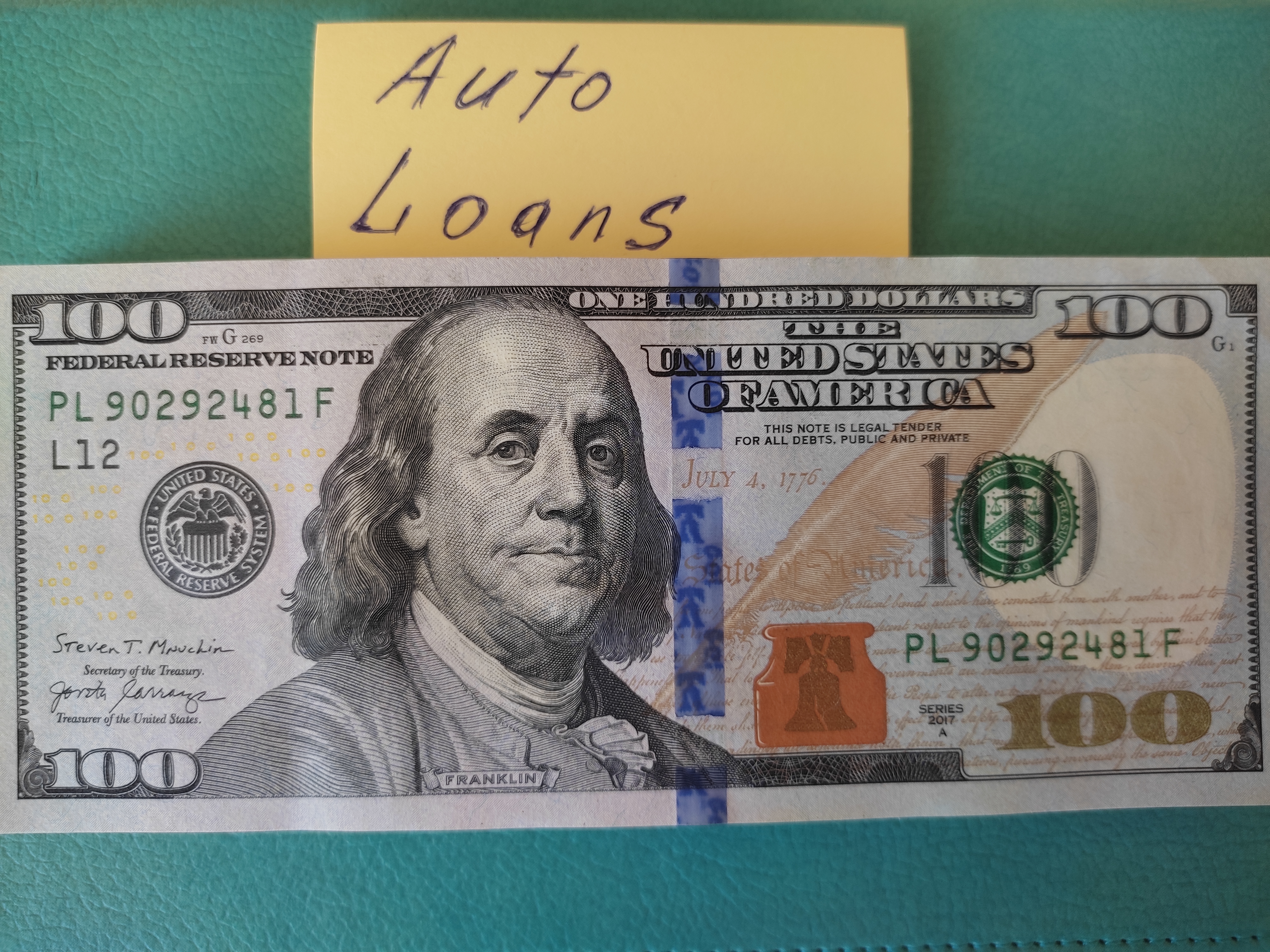 There are money on the table and a sticker, where it is written auto loans.
