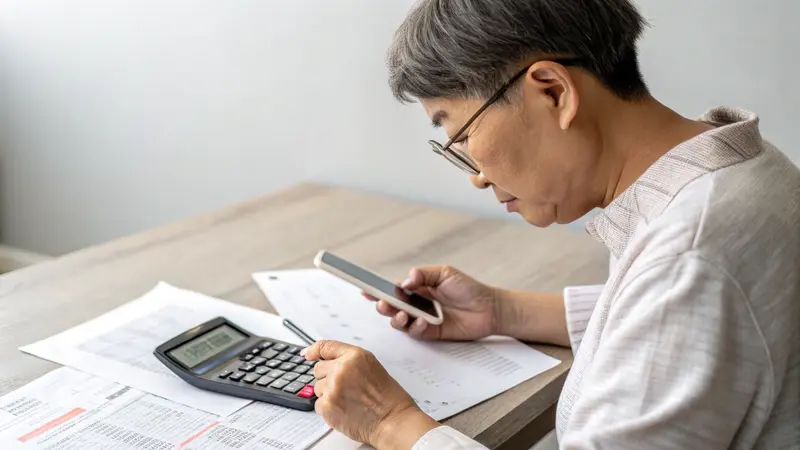 Person reviewing payday loan documents with calculator and smartphone